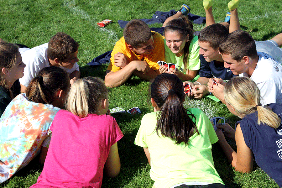 Members of the Arlington Cross Country team play a card game on the grass at the 12 hour relay on September 9.