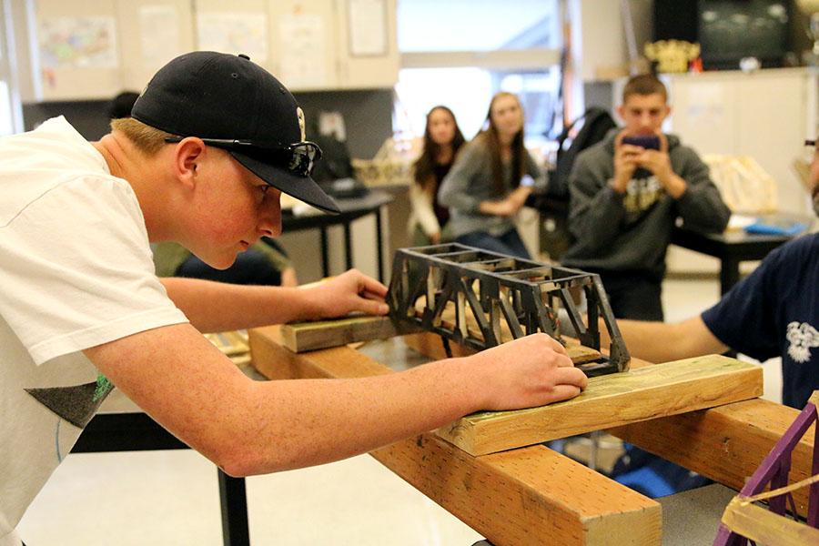 Sophomore Isaiah Mitzelfeldt prepares his bridge to support the weight of dampened sand to test the structural integrity of the bridge.