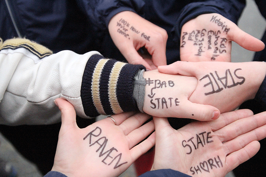 Varsity+XC+girls+display+the+motivational+words+written+on+their+hands+during+their+meet.