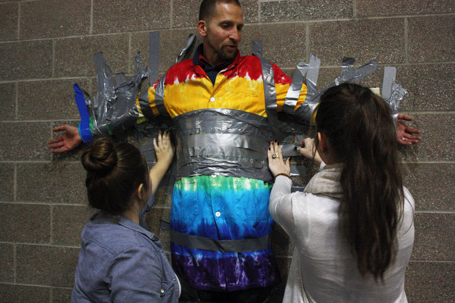 Students tape Mr. Murray to the lunchroom wall during a fundraiser this past week