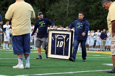 During a football game against East Side Catholic, Brett Deberry (left) and Joe Colter (right) walked out onto the AHS football field to give Jonielle Spillers a frame of her son’s jersey, Jojo Mangual, who was one of the deceased victims in the mudslide.