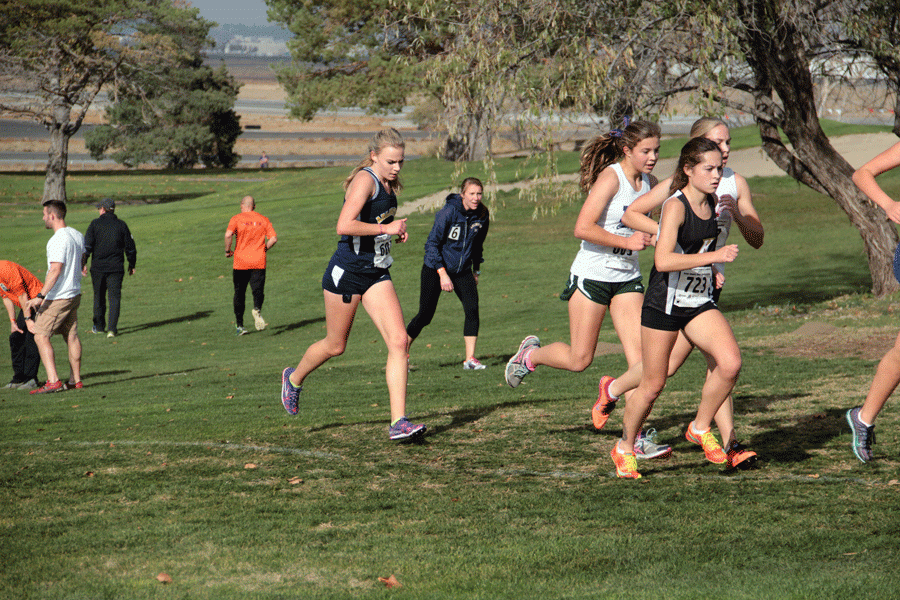 Mary Andrews (18) competes at the Cross Country State tournament while Coach Piccolo cheers her on in November.
