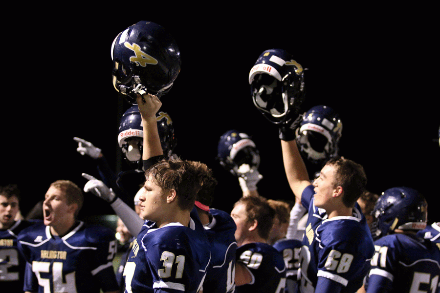 After a 22-20 win against Stanwood on Friday, 14th, Payton Bastin (18) and Nick Galusha (18) hold their helmets in the air along with their teammates after the victory. 