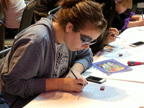 Spanish Club president Hannah Novy works on an art piece during the festival. Her face is painted in the traditional style as well. 