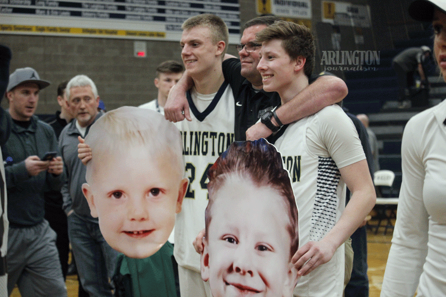 Drew Bryson (17) and Sam Tregoning (17) pose with their baby pictures on boys basketball senior night. 