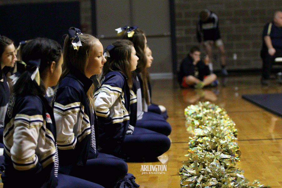 The varsity cheerleaders sit on the floor as they cheer at the first match of the year against Kamiak.