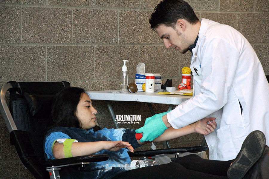 Yese Perez (12) watches as a Bloodworks staff member starts to insert the needle into her arm during the Blood Drive on October 23rd.