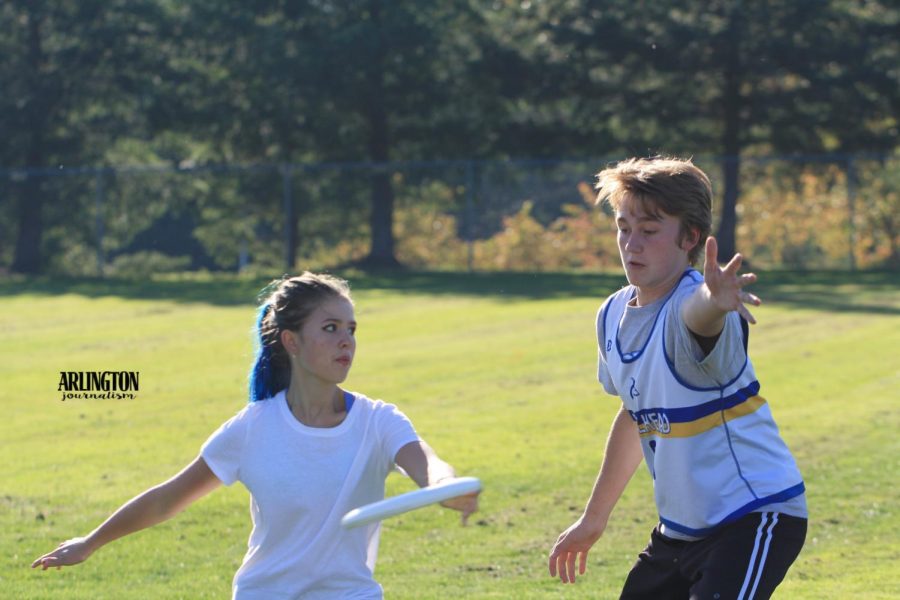 Hailey Pawley (11) throws a frisbee while Sam Schroeder (10) defends.