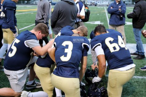 Luke Zachman (11), Andrew Brotherton (11), and Quintin Yon-Wagner (10) kneel before their game to pray. 