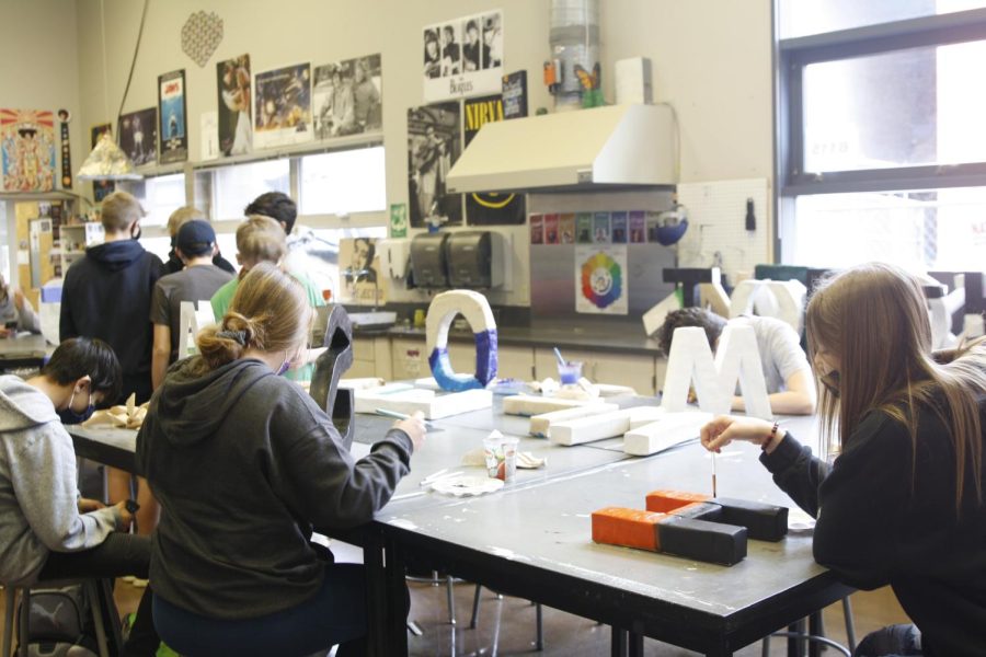 Art students work on painting letter sculptures in Graphics 1. 