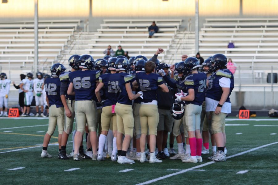 The junior varsity football team is pictured huddling following a game. 