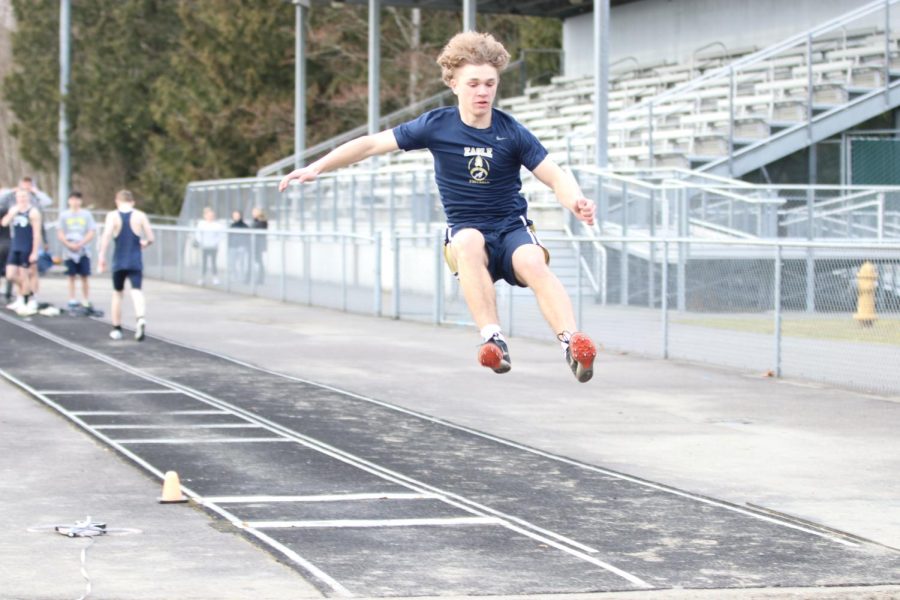 A student on the track team is seen performing long jump.
