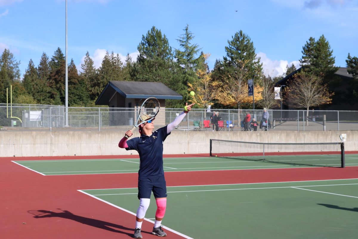 Xander Carroll (27) warms up before a match. Carroll made it on the varsity tennis team. He enjoys tennis because he is able to play with his doubles partner Easton Aalbu. Carroll said it was fun finding the rhythm and “to get better as the year goes on.” 